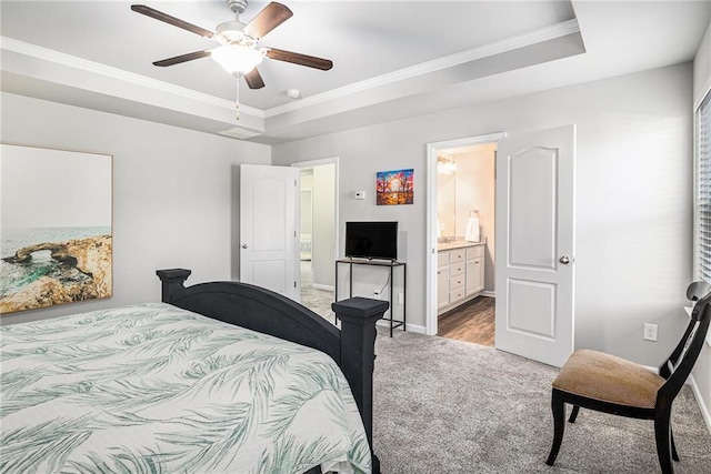 bedroom featuring baseboards, a raised ceiling, light colored carpet, ensuite bathroom, and crown molding