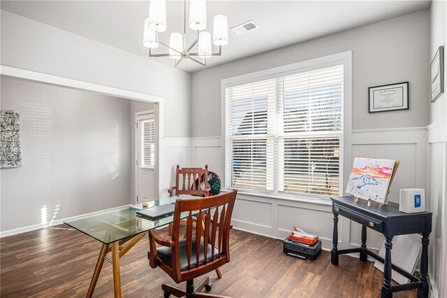 office space with a notable chandelier, wood finished floors, visible vents, and a decorative wall