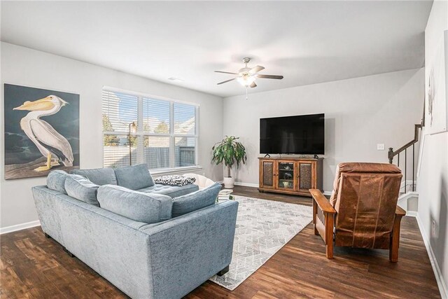 living room with stairs, dark wood finished floors, a ceiling fan, and baseboards