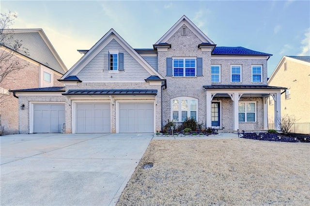 view of front of home featuring an attached garage, a standing seam roof, concrete driveway, and brick siding