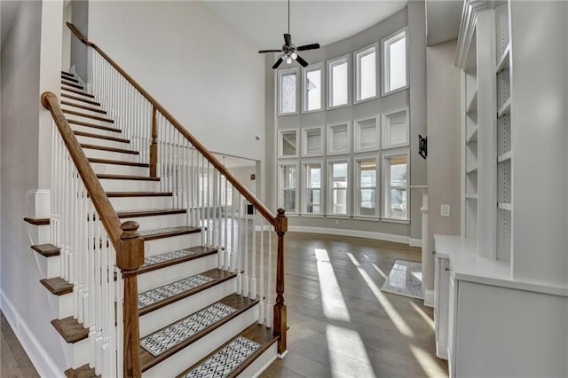 foyer with baseboards, ceiling fan, hardwood / wood-style floors, a high ceiling, and stairs