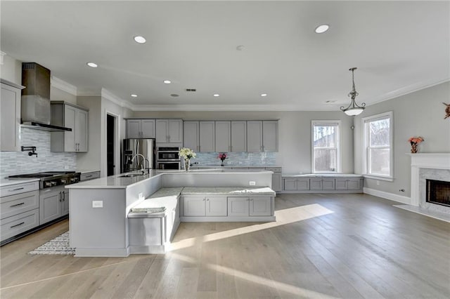 kitchen with appliances with stainless steel finishes, gray cabinetry, light countertops, and wall chimney exhaust hood