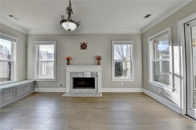 unfurnished living room with light wood finished floors, a premium fireplace, visible vents, and crown molding