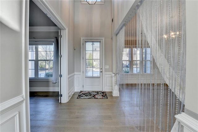 foyer featuring wainscoting, wood finished floors, an inviting chandelier, and a decorative wall