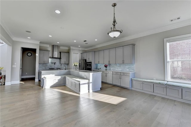 kitchen featuring wall chimney exhaust hood, gray cabinets, visible vents, and stainless steel fridge with ice dispenser