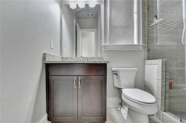 full bathroom with a stall shower, baseboards, vanity, and toilet