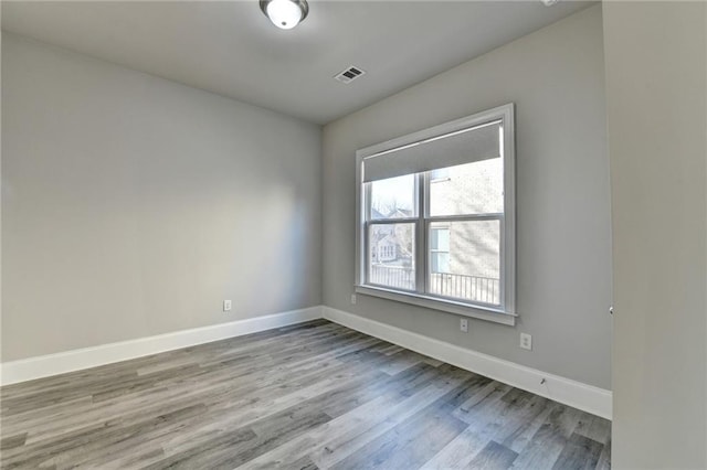 spare room featuring visible vents, baseboards, and wood finished floors