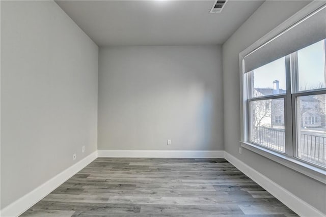 unfurnished room with baseboards, visible vents, and wood finished floors