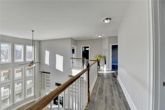 corridor featuring baseboards, an upstairs landing, and wood finished floors