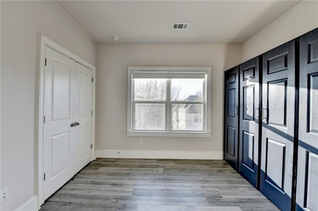 interior space featuring light wood-style floors, visible vents, and baseboards