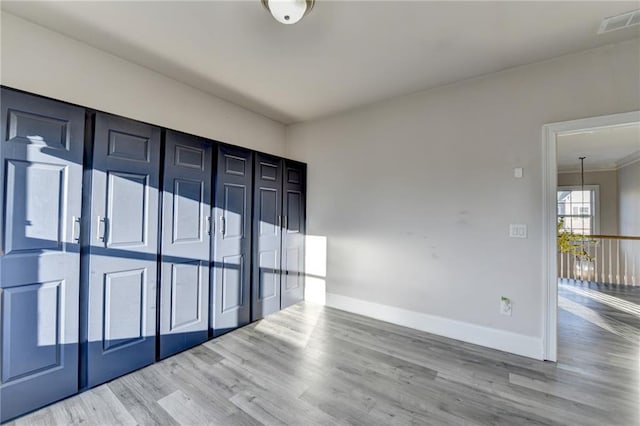 empty room featuring wood finished floors, visible vents, and baseboards