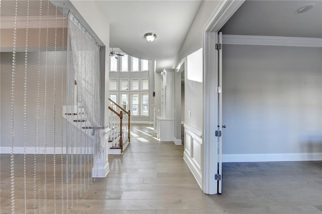 foyer entrance featuring ceiling fan, wood finished floors, baseboards, ornamental molding, and stairway