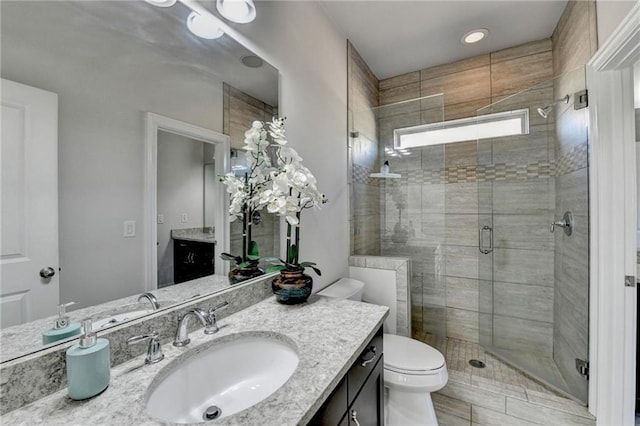 full bathroom with toilet, a stall shower, and vanity