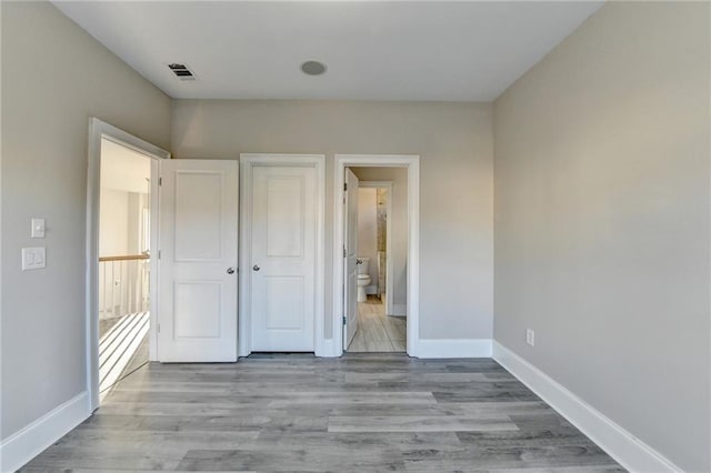 unfurnished bedroom with wood finished floors, visible vents, and baseboards