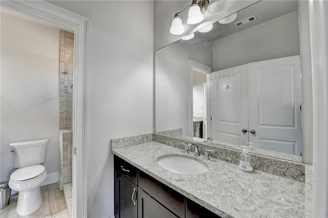 bathroom featuring toilet, vanity, visible vents, and baseboards