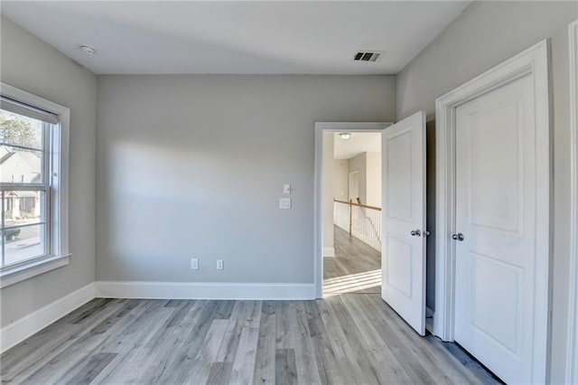 unfurnished bedroom featuring light wood-type flooring, baseboards, and visible vents