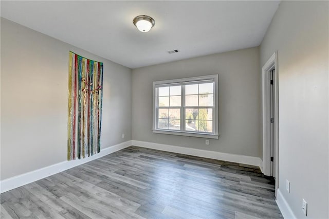 empty room featuring visible vents, baseboards, and wood finished floors