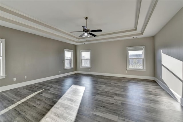 unfurnished room with ornamental molding, dark wood-style flooring, plenty of natural light, and a raised ceiling