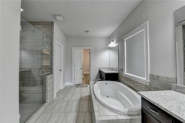 full bath featuring a stall shower, baseboards, visible vents, a garden tub, and vanity