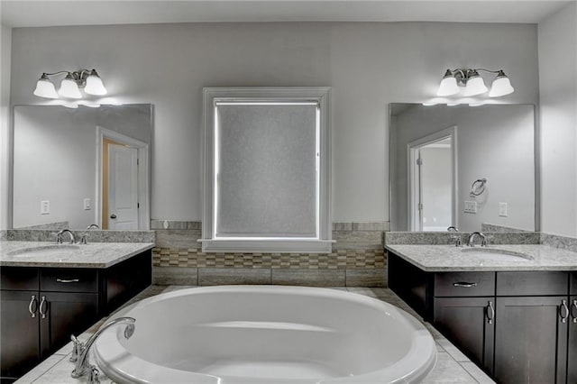 full bath featuring a bath, two vanities, and a sink