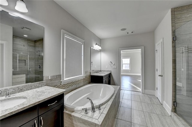 full bath featuring visible vents, a sink, a shower stall, and a garden tub