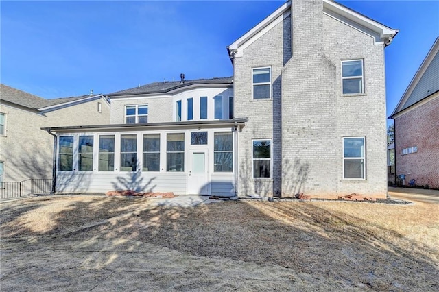 rear view of property with brick siding and a sunroom