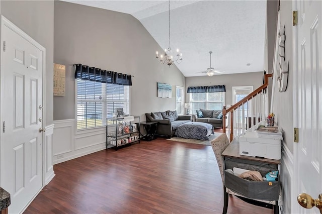 entryway featuring ceiling fan with notable chandelier, a healthy amount of sunlight, dark wood-type flooring, and high vaulted ceiling