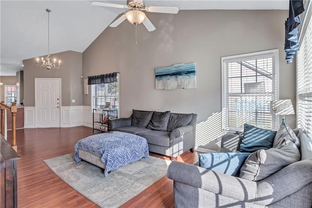 living room with dark hardwood / wood-style flooring, high vaulted ceiling, a healthy amount of sunlight, and ceiling fan with notable chandelier