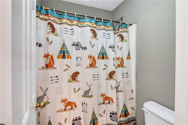 bathroom featuring a textured ceiling, toilet, and walk in shower