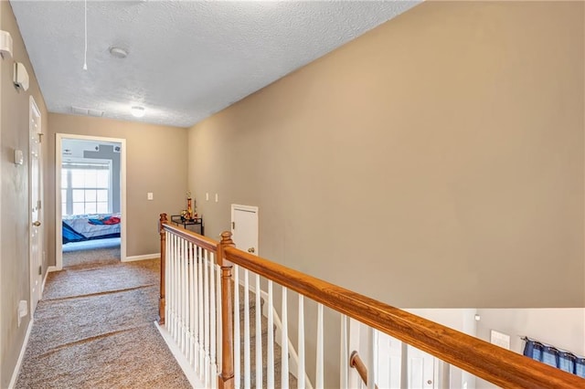 hall with light colored carpet and a textured ceiling