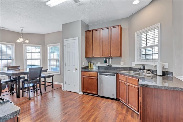 kitchen featuring sink, stainless steel dishwasher, a textured ceiling, decorative light fixtures, and wood-type flooring