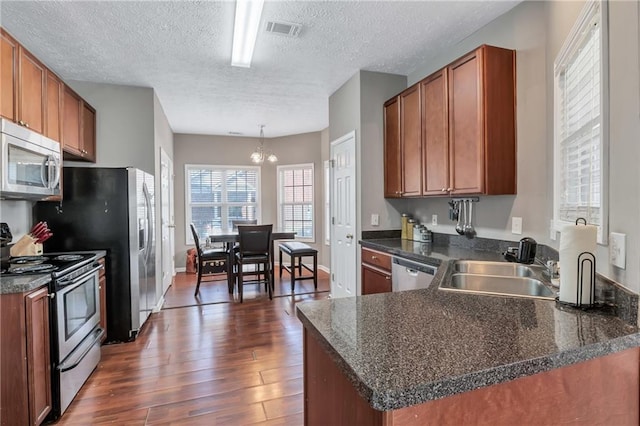 kitchen featuring pendant lighting, dark hardwood / wood-style floors, a textured ceiling, kitchen peninsula, and stainless steel appliances