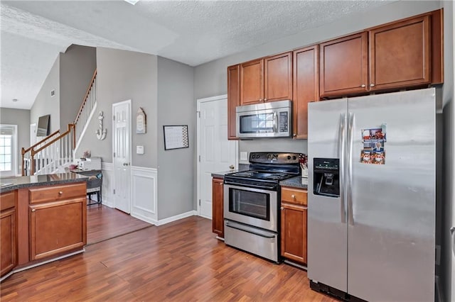 kitchen featuring a textured ceiling, stainless steel appliances, vaulted ceiling, and dark hardwood / wood-style floors