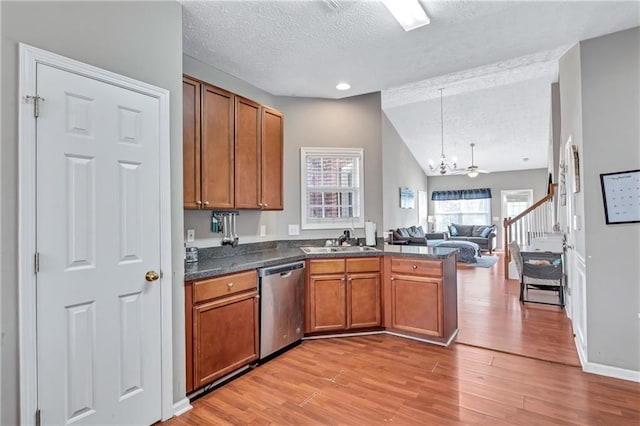 kitchen featuring light wood-type flooring, a textured ceiling, vaulted ceiling, sink, and dishwasher