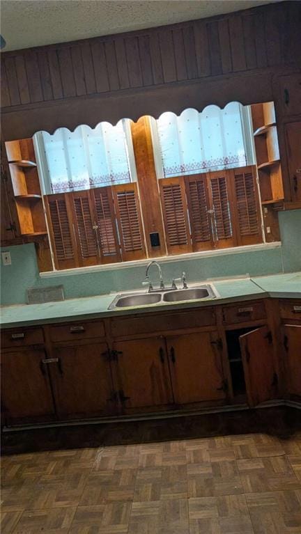 kitchen with a textured ceiling, open shelves, a sink, and light countertops