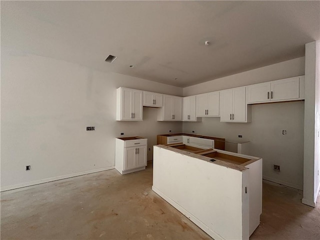 4428 Ryan St, Douglasville, GA 30135 - kitchen featuring a kitchen island, unfinished concrete floors, white cabinetry, and baseboards
