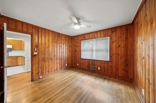 empty room with baseboards, ceiling fan, visible vents, and hardwood / wood-style flooring