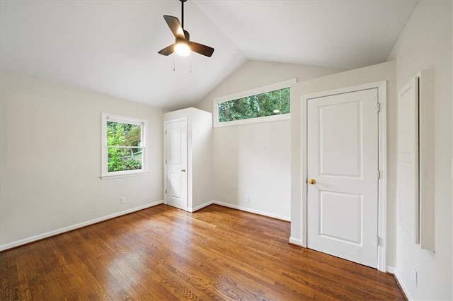 unfurnished bedroom featuring baseboards, multiple windows, vaulted ceiling, and wood finished floors