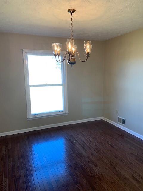 empty room featuring dark hardwood / wood-style floors and a notable chandelier