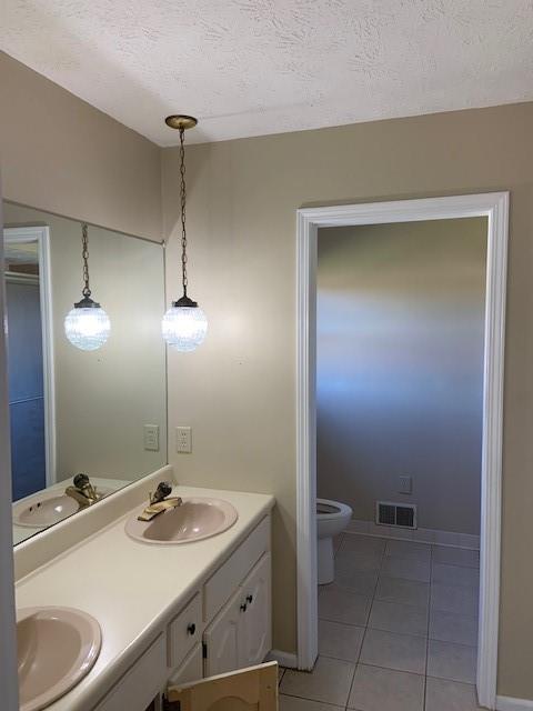 bathroom featuring a textured ceiling, tile patterned flooring, vanity, and toilet