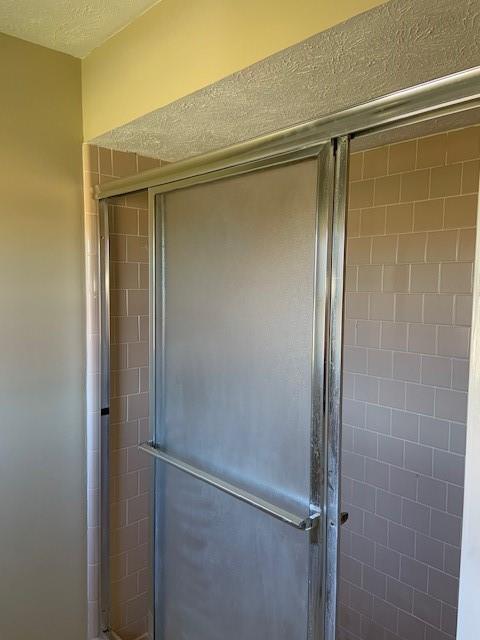 bathroom featuring a textured ceiling and a shower with door