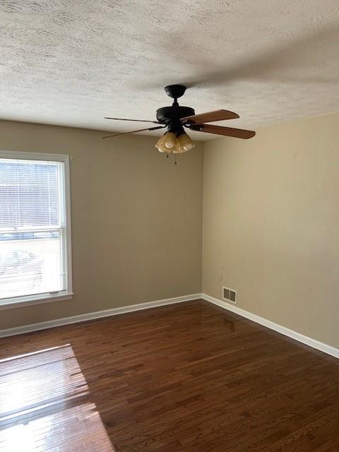 empty room with dark wood-type flooring, ceiling fan, and a textured ceiling