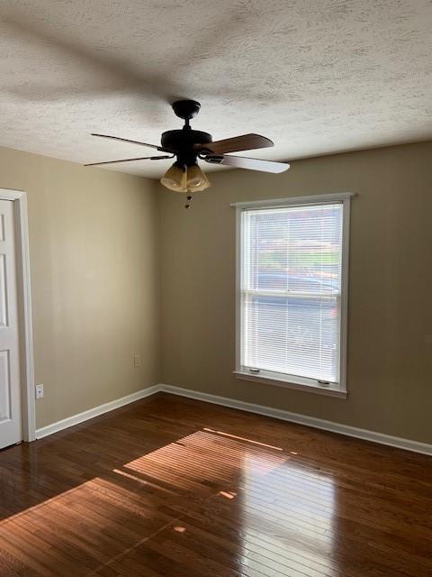 unfurnished room with ceiling fan, dark hardwood / wood-style floors, and a textured ceiling