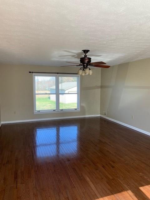 spare room with ceiling fan, dark hardwood / wood-style flooring, and a textured ceiling