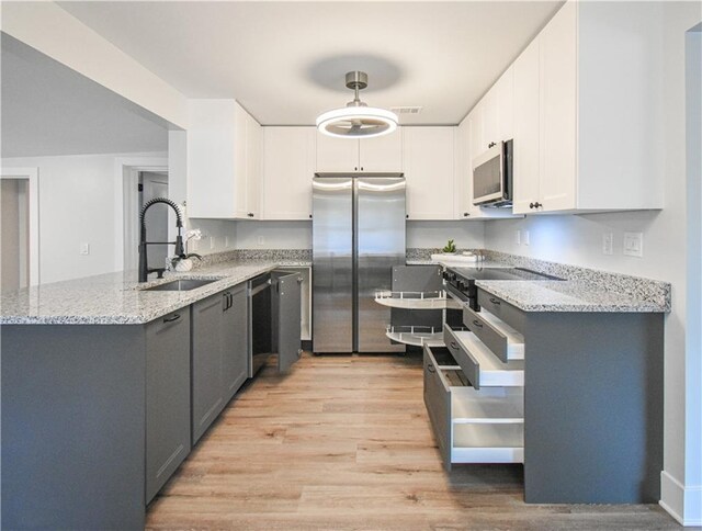 spare room featuring a ceiling fan, a wealth of natural light, light wood finished floors, and baseboards