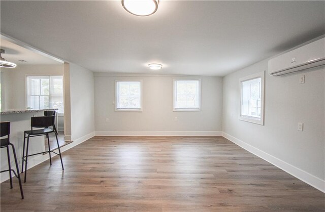 empty room featuring a wall unit AC and light hardwood / wood-style floors