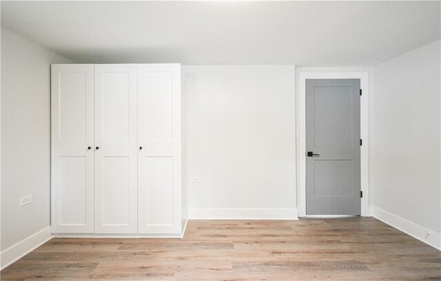 spare room featuring light wood finished floors and baseboards