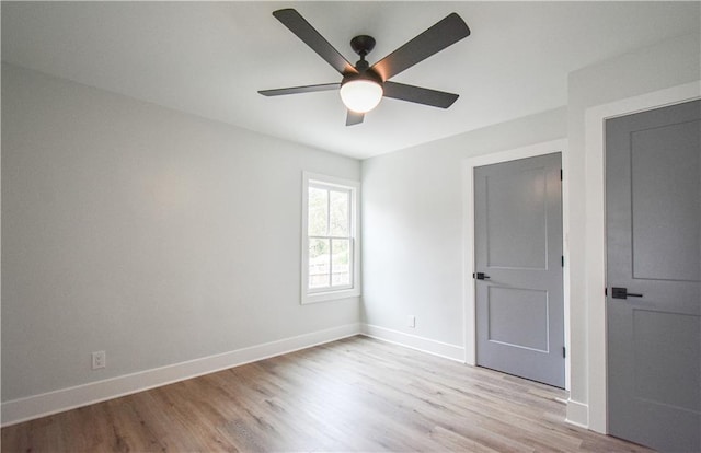 empty room featuring ceiling fan, light wood-style floors, and baseboards