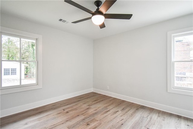 empty room featuring light wood finished floors, baseboards, visible vents, and ceiling fan