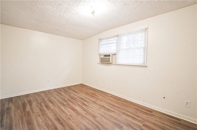 unfurnished room featuring baseboards, a textured ceiling, cooling unit, and wood finished floors